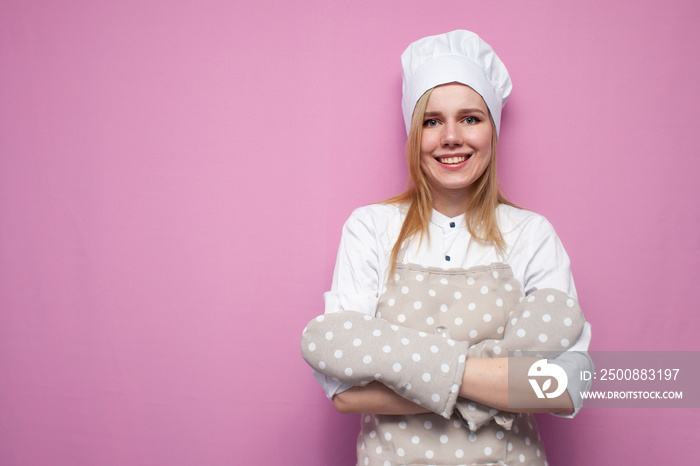 Portrait of a funny girl cook in uniform, apron and gloves for baking on a colored background, a beautiful woman is a housewife in kitchen clothes smiling