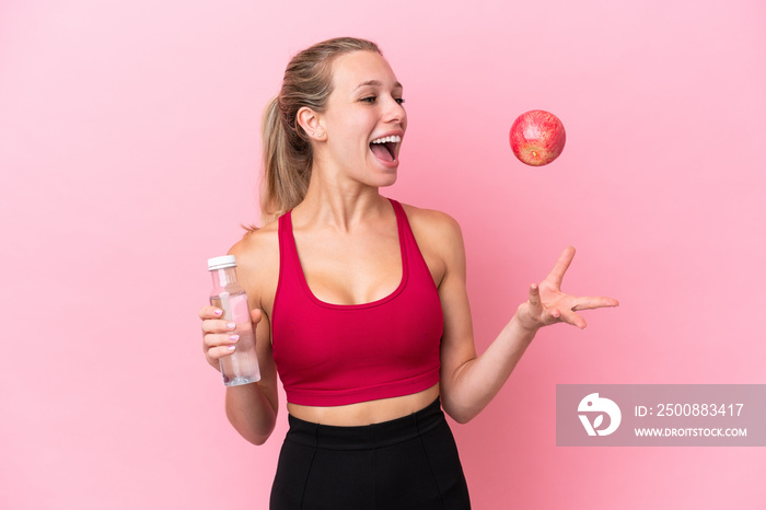 Young caucasian woman isolated on pink background with an apple and with a bottle of water