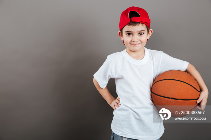 Smiling little boy in cap with orange basketball ball