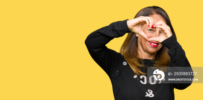 Beautiful middle age woman wearing rock and roll sweater Doing heart shape with hand and fingers smiling looking through sign