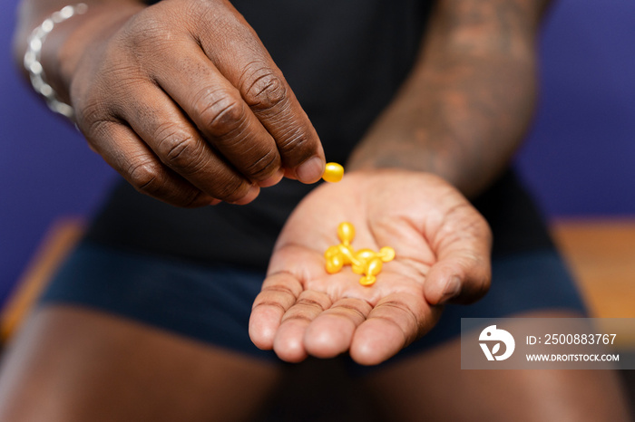 Close-up of man holding yellow capsules in hands