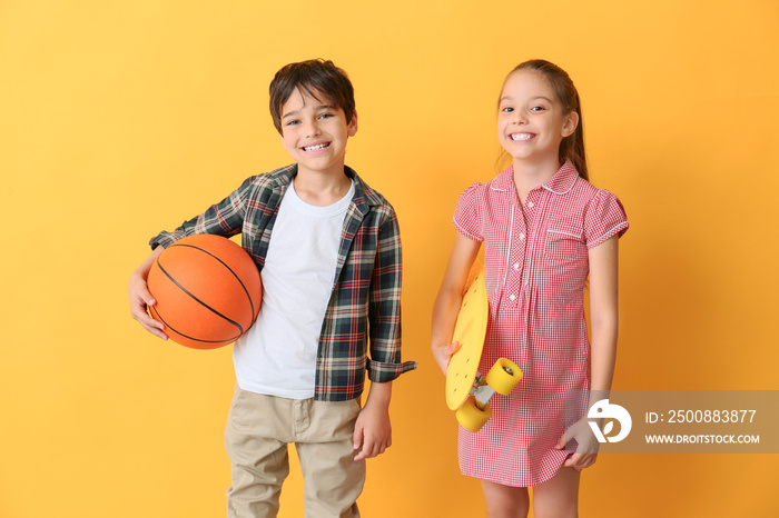 Cute little children with ball and skateboard on color background