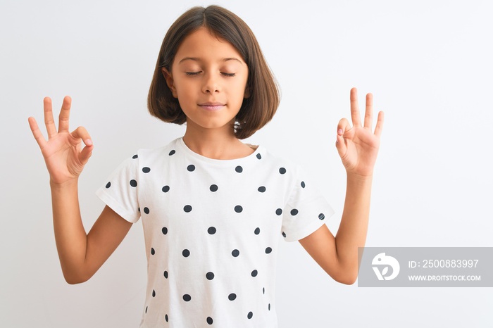 Young beautiful child girl wearing casual t-shirt standing over isolated white background relax and smiling with eyes closed doing meditation gesture with fingers. Yoga concept.