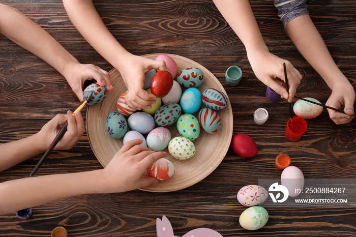 Cute little children painting eggs for Easter at table