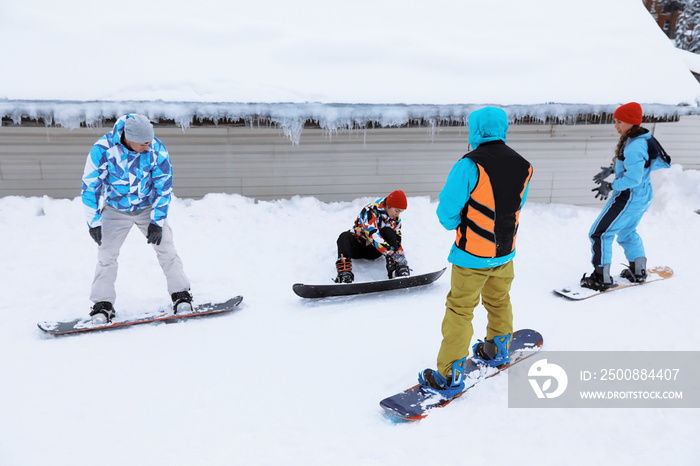 Group of friends taking snowboard lessons at snowy resort. Winter vacation