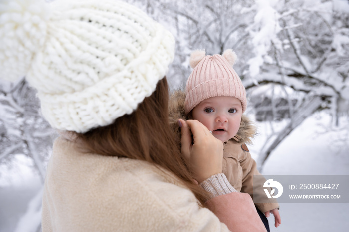 A young mother with a small child plays in the snow, they are having fun and enjoying the snowfall. Winter walk outside.