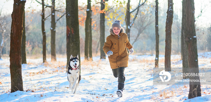 Running boy with husky on a distillation in a winter park