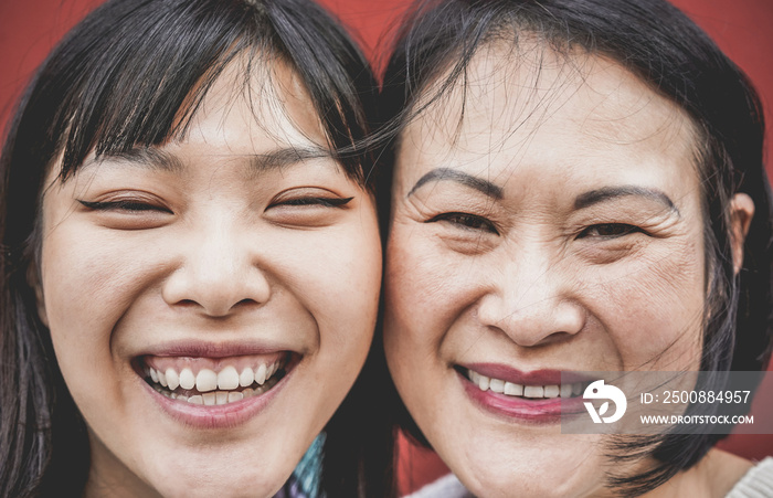 Portrait of asian mother and daughter laughing in front of camera - Focus on left girl face