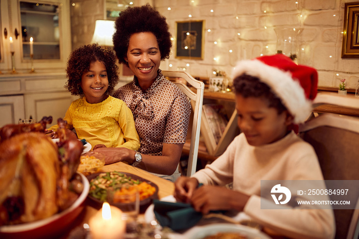 Happy African American family enjoys at dining table during Christmas dinner.