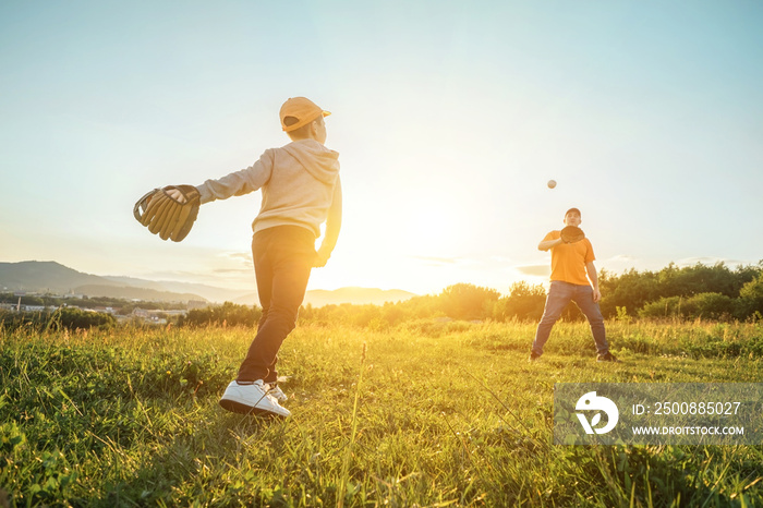 Father and son playing in baseball. Playful Man teaching Boy baseballs exercise outdoors in sunny day at public park. Family sports weekend. Father’s day.