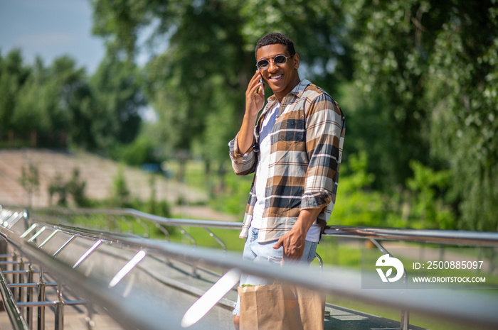 Man in sunglasses and plaid shirt talking on the phone