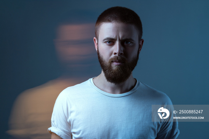 Double exposure crative portrait of artistic bearded model man in white t-shirt looking at camera with calm serious face. special blurred beauty effect. indoor studio shot.