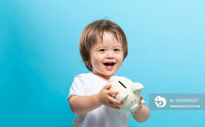 Toddler boy with a piggy bank on a blue background