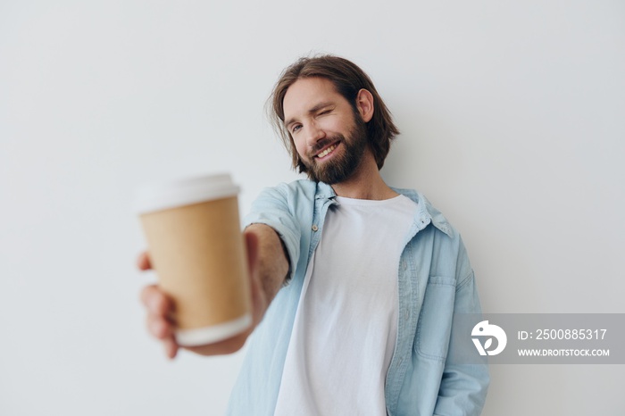 Freelance Millennial man with a beard drinking coffee from a recycled cup in stylish hipster clothes white T-shirt blue jeans and shirt on a white background