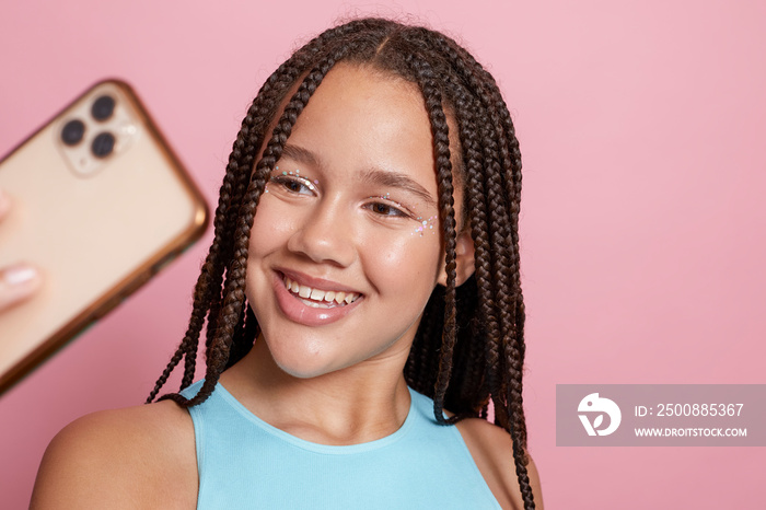 Studio shot of smiling girl with braids holding smart phone