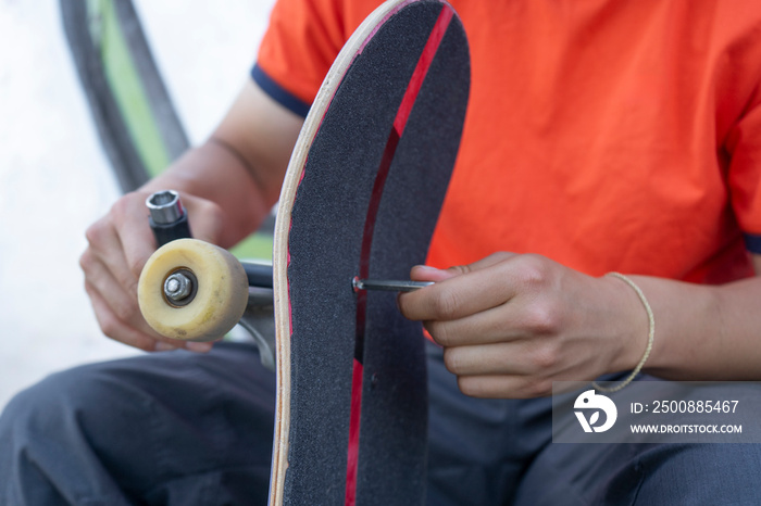 Close-up of young man fixing skateboard