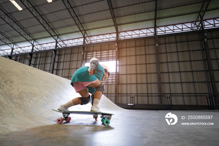 asian child or kid girl playing skateboard or surf skate and get off the ramp or down from wave ramp to bottom turn hand touching floor in skatepark by extreme sports to wearing helmet and body safety