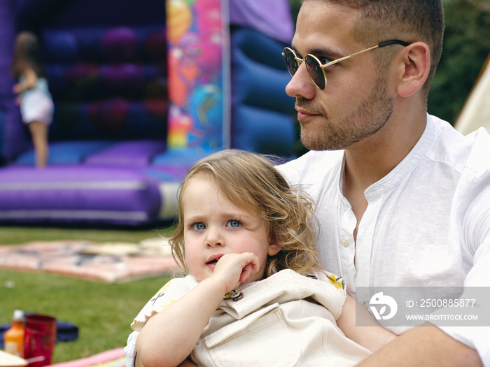 Father holding daughter at outdoor party