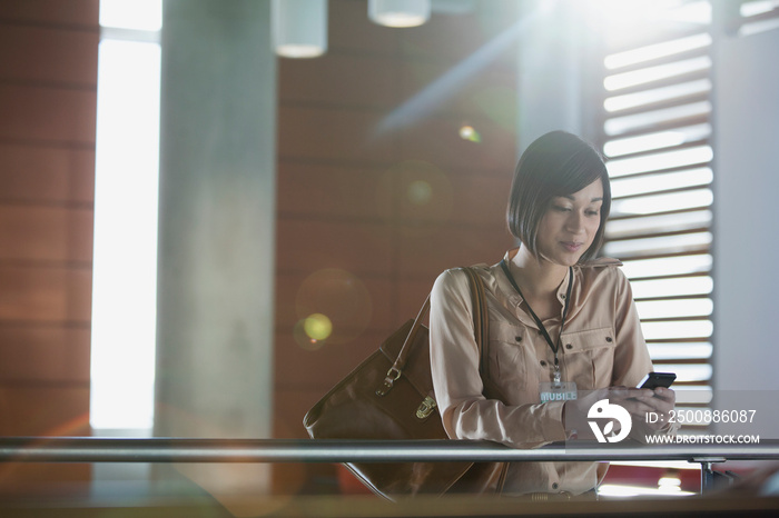 Stylish woman checking cell phone in hallway