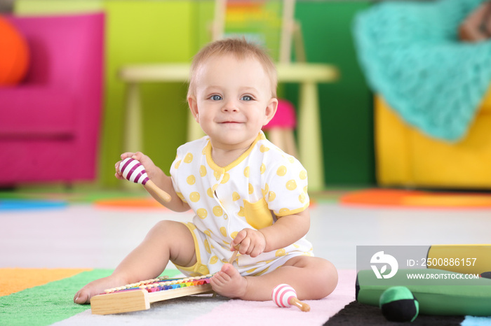 Cute little baby playing with musical instruments at home