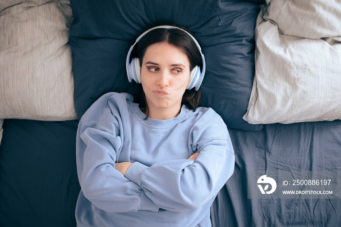 Stressed Woman Wearing Headphones Lying in Bed