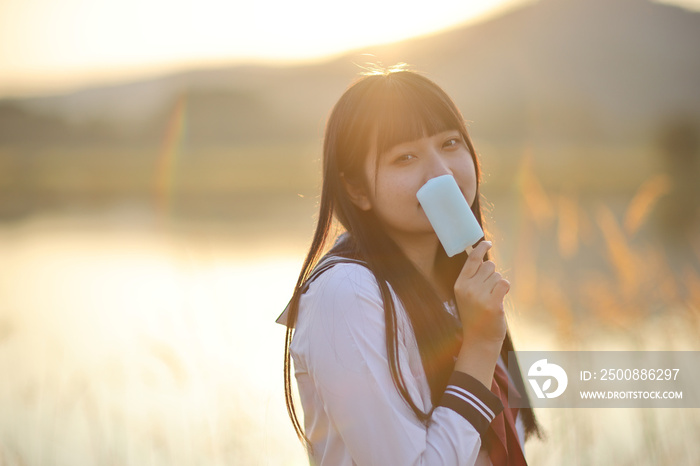 Asian High School Girls student eating ice cream in countryside with sunrise