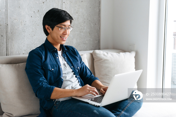 Smiling young asian man sitting on a couch