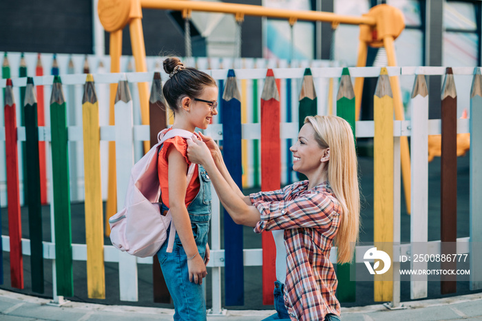 Mom saying goodbye to her daughter before going to school. Back to school and education concept.