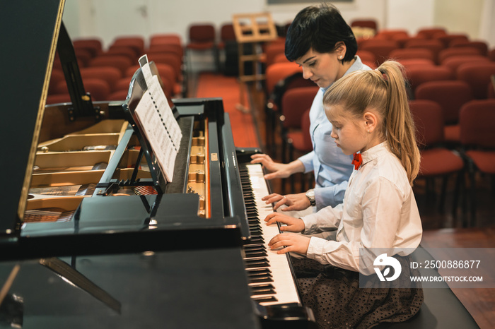 little girl practicing playing piano with her professor assistance