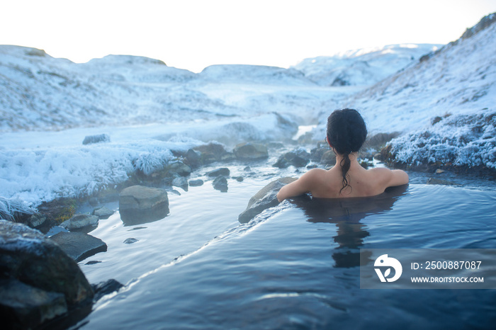 The girl bathes in a hot spring in the open air with a gorgeous view of the snowy mountains. Incredible iceland in winter