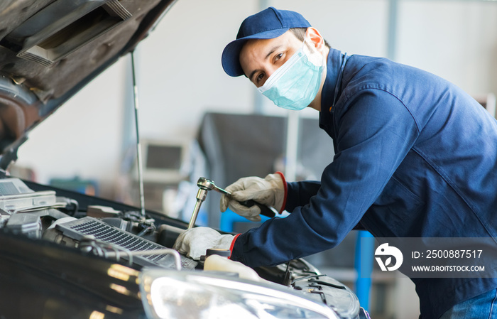 Mechanic repairing a car, covid concept