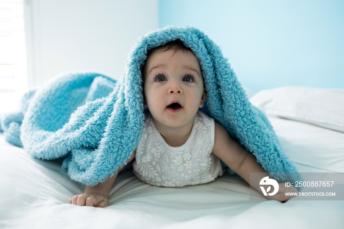 Cute baby girl under the blanket on bed