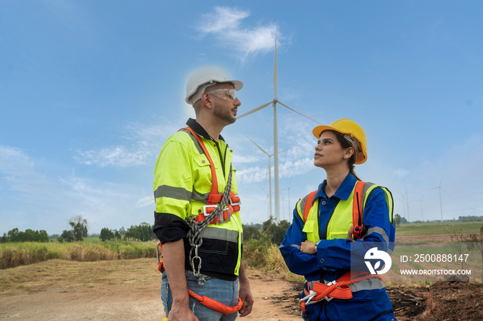 Male and female engineers, colleague installers, inspecting wind turbines, bringing wind energy, generating electricity in a wind turbine field.