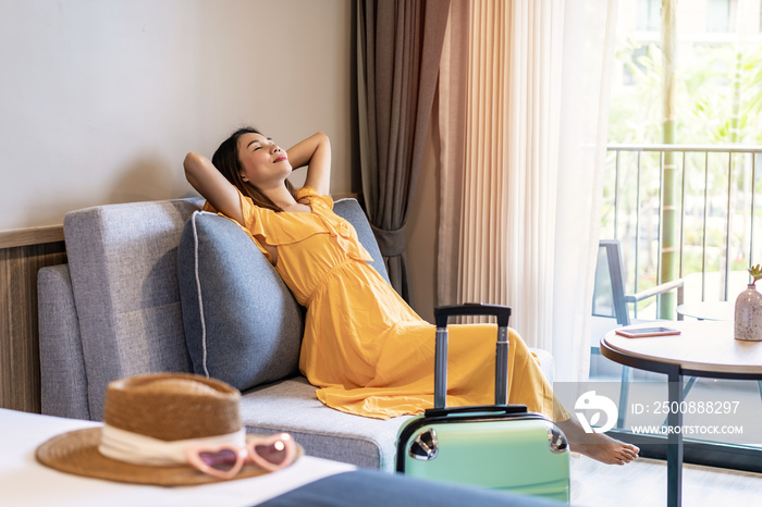 Young woman traveler sitting and relaxing in a hotel room while on summer vacation, Travel lifestyle concept