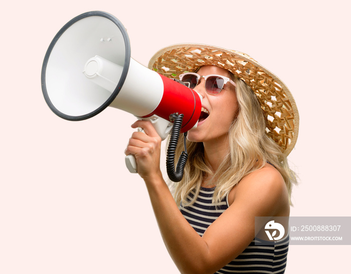 Young woman using sunglasses wearing summer hat communicates shouting loud holding a megaphone, expressing success and positive concept, idea for marketing or sales