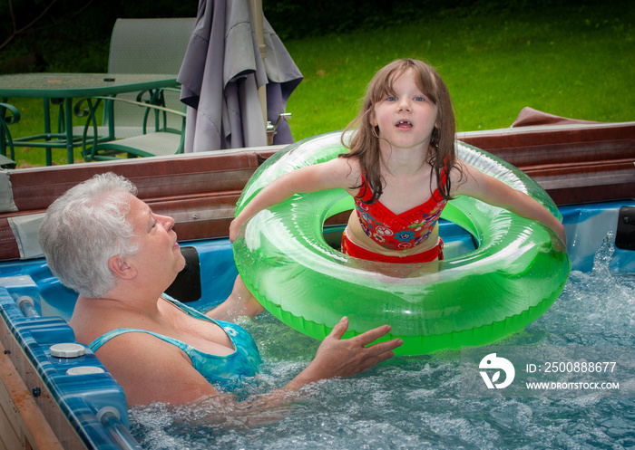 Grandmother and Granddaughter enjoying a Summer Day in the Spa.  Woman and child in a hot tub with round floaty!