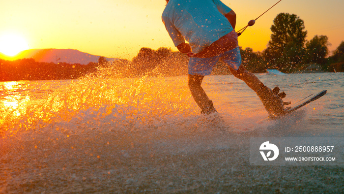 LENS FLARE: Wakeboarder does a 180 ollie while riding around the cable park.