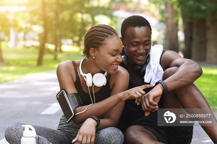 Black Couple Using Smartwatch Fitness Tracker After Outdoor Workout, Checking Burned Calories