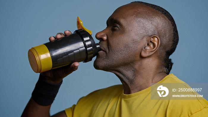 Close-up tired athletic man athlete taking break during training drinking cool fresh water from sports bottle quenches thirst after exercise adult african american sportsman enjoying protein drink