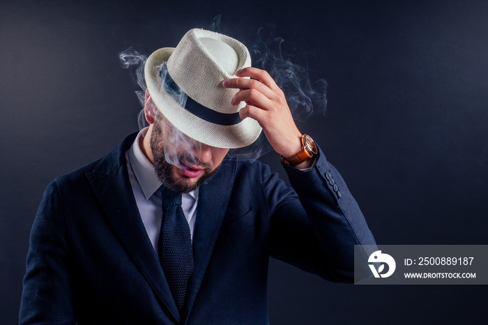 Portrait of an attractive business man with a cigar in black background studio