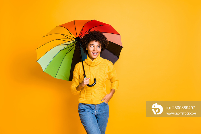 Bad weather but good mood concept. Photo of positive optimistic cheerful shiny person holding hiding under multicolored accessory in hand walking on street in casual jeans isolated bright background