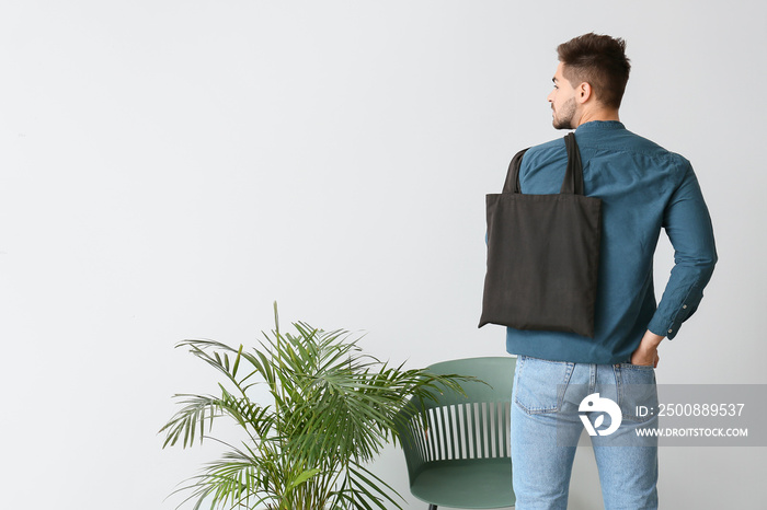 Young man with eco bag against light wall