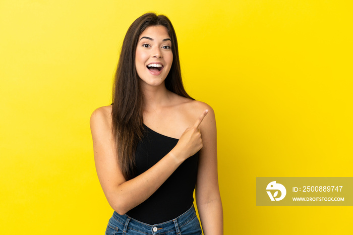 Young Brazilian woman isolated on yellow background surprised and pointing side