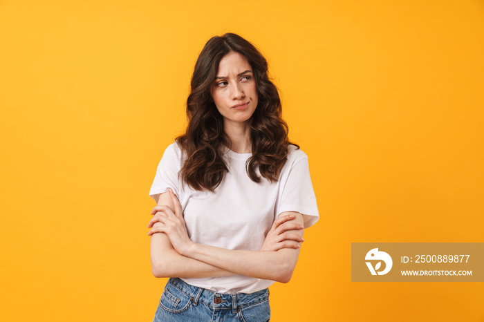 Sad displeased young woman posing isolated over yellow wall background.