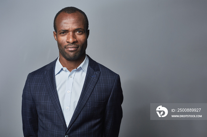 Confident look. Waist-up portrait of successful young african businessman is wearing in formal clothes and looking at camera assertively. Isolated background with copy space