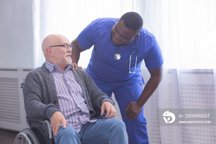 Caregiver and old man in a wheelchair. Professional nurse and patient in a nursing home. Assistance, rehabilitation and health care.