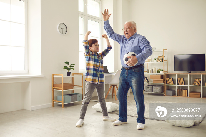 Happy football fans: Cheerful grandfather and excited teen grandson enjoying free time at home, having fun together, playing sports games and celebrating victory of their favorite team