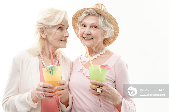 Carefree senior female friends drinking cocktails