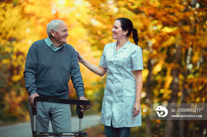 Nurse helping elderly senior man. Senior man using a walker with caregiver outdoor