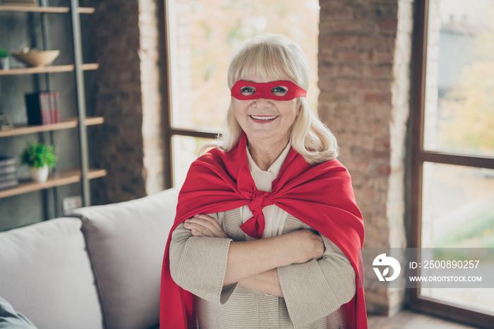 Close-up portrait of her she nice attractive cheerful cheery gray-haired lady wearing red costume super nanny planet save rescue service folded arm at industrial brick loft modern style interior house